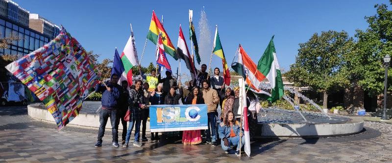 Group of international students at ISU holding their countries's flags infront of the fountain